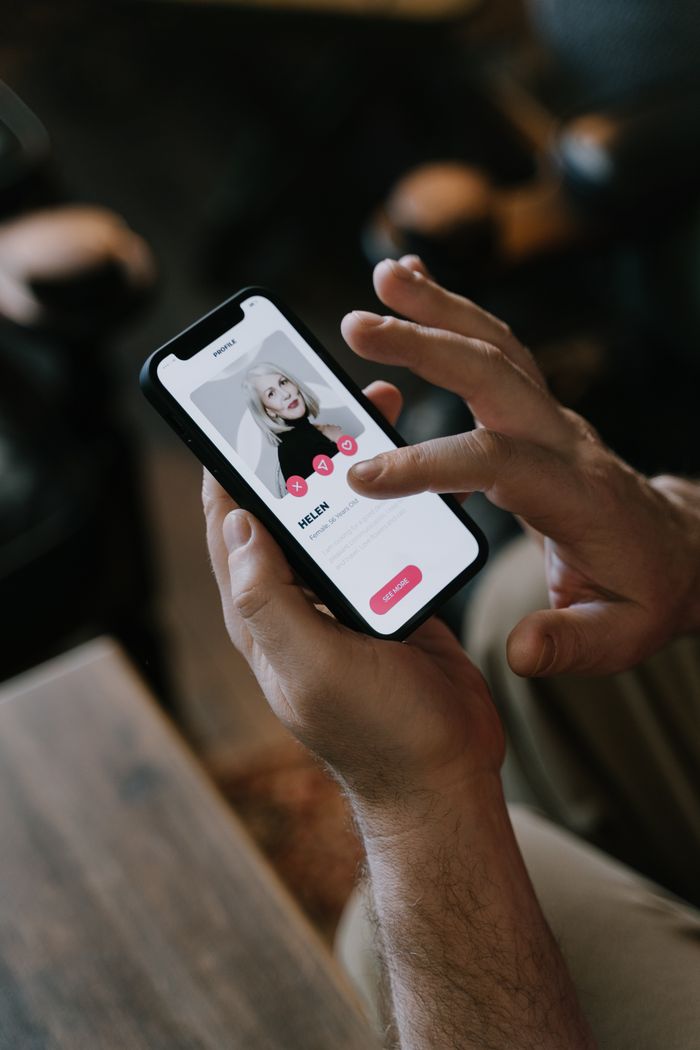 Mastering the First Impression: Your intriguing post title goes here Close-up of hands using a dating app on a smartphone indoors. Modern technology and online dating.